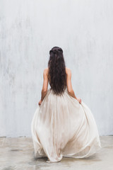 Fototapeta na wymiar Girl with long black hair in a gentle silk wedding dress