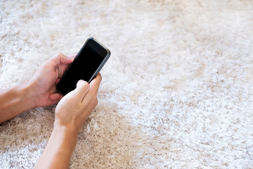 Hand using smart phone on white carpet, selective focus