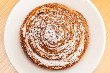 Powdered sugar sweet roll bun on table, top view