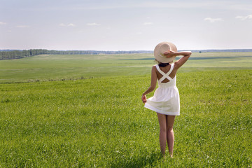 Naklejka na ściany i meble young girl with long dark hair standing on a green field