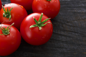 Red cherry tomatoes on black rustic wood background