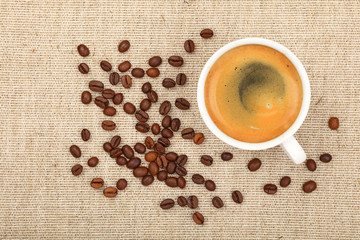 Full espresso cup and coffee beans on canvas