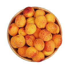 Ripe fresh apricots in wooden bowl over white