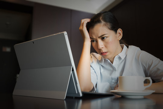 Frustrated businesswoman having headache hold hand head upset while working, sitting using taplet Laptop Computer, work failure stress and problems Concept.