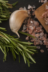 Salt, pepper, garlic and rosemary on a chopping board