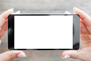 Hand holding mobile phone with blank screen. Taking photo on blurred wooden background
