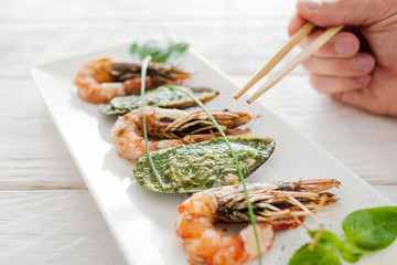 Seafood eating with chopsticks, close-up. Dining at asian restaurant with special cutlery