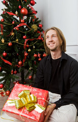 Obraz na płótnie Canvas portrait of a young man with long hair under the Christmas tree
