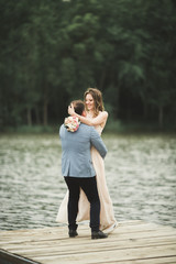 Fototapeta premium Groom carrying bride near lake and forest