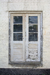 Alte morsche Holztür mit Sprossenfenstern und abgeblätterter weißer Farbe 