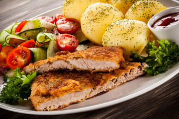 Fried pork chops, boiled potatoes and vegetable salad 
