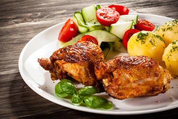Barbecued chicken legs with boiled potatoes and vegetables 