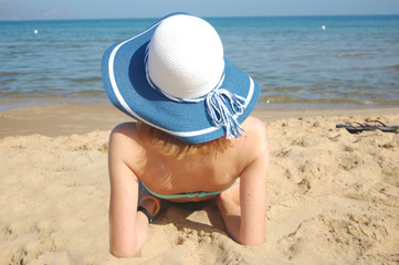 Fototapeta na wymiar Young lady sunbathing on the sandy beach of the Tyrrhenian sea in July. Relaxing
