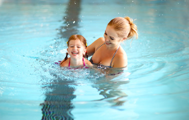 mother teaching child daughter swimming pool