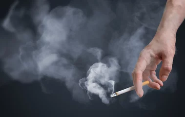 Fototapeten Raucher hält rauchende Zigarette in der Hand. Viel Rauch herum. © vchalup