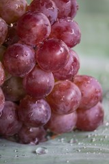 Bunch of red grapes , fresh with water drops isolated on banana leaf background , Close up , Low key photo natural light , Focus sharp specific point