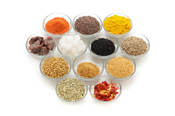 Different types of Indian spices in glass bowls isolated on white background. Elevated view.