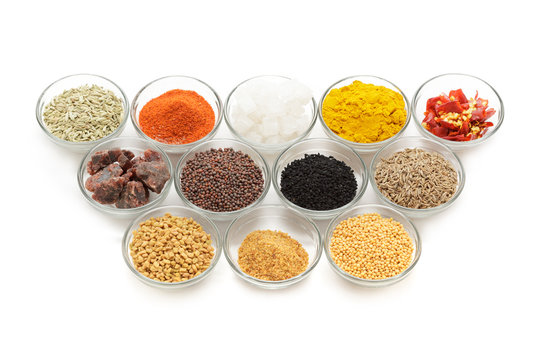 Different types of Indian spices in glass bowls isolated on white background. Elevated view.