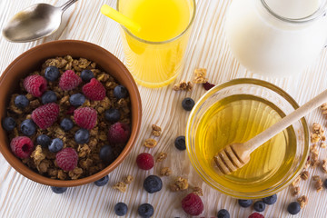 Muesli with fresh berries, honey, milk and orange juice.