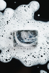 Coal soap in foam on black © dariazu