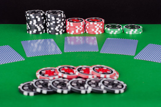 green casino table with covered playing cards, red and black chi