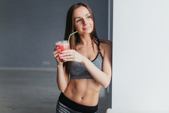 Sports girl after exercise relaxes in a bright room and cocktail drinks