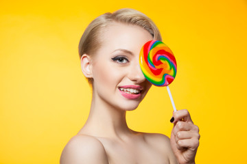 Model covering eye with lollipop and smiling at camera