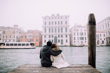 Loving couple sitting on the pier in Venice, Italy