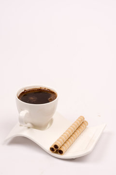 White cup of coffee with wafer chocolate cream rolls