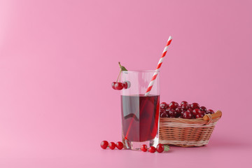 Glass of fresh juice with cherries on bright background