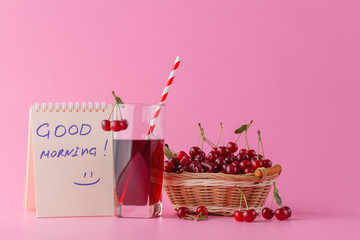 Sweet cherries in a basket and glass of juice on pink  backgroun
