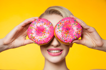 Short-haired model covering eyes behind two pink donuts