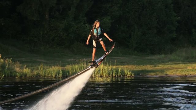 Young girl on the Hover board on the river, water jet spray.Young girl on the flying board flies over the lake water.Fly board rider.