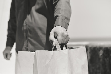 Closeup on hand holding paper bag, bright light background