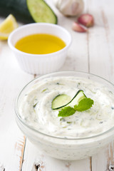 Tzatziki and ingredients on white wooden table

