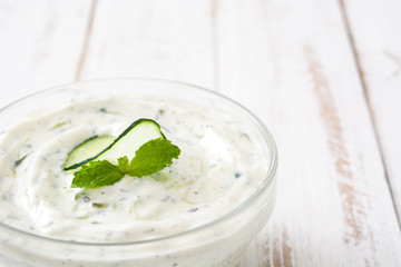 Tzatziki in bowl on white wooden table

