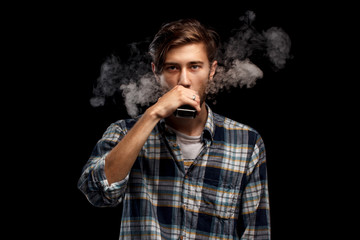 Man using an advanced personal vaporizer or e-cigarette. Black background.