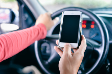 Closeup on hand holding smartphone in a car interior background