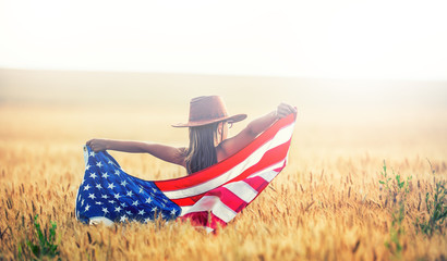Pretty young pre-teen girl with an American cowboy hat in corn field and the holding American flag. © weyo