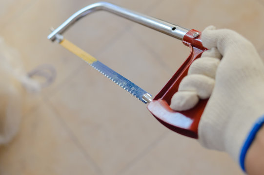 Closeup view of hand holding coping saw, indoors background