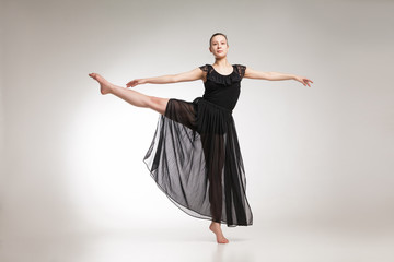 Young ballet dancer wearing black transparent dress dancing 