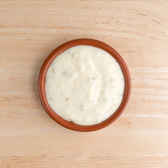 Small bowl of tartar sauce on a wood table top view.
