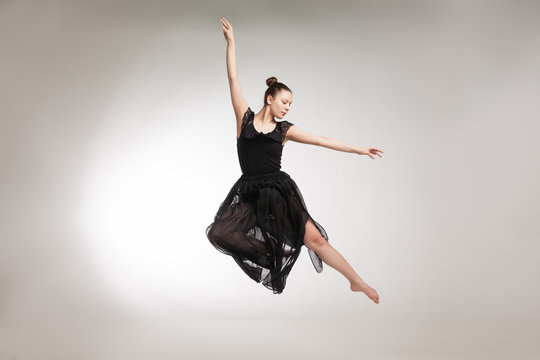 Young ballet dancer wearing black transparent dress jumping 