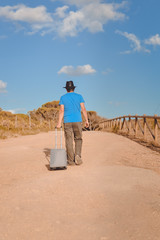 View of man from the back on a long country road outside blue sky background