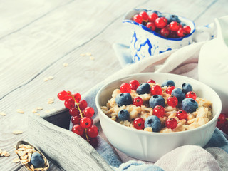 Breakfast with oatmeal porridge and fresh berries. Toned image
