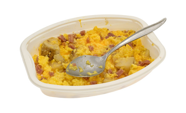 Ham eggs and potatoes breakfast TV dinner in a tray on a white background.