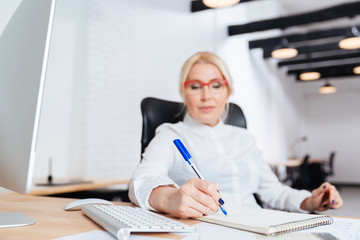 Businesswoman writing in notebook in office