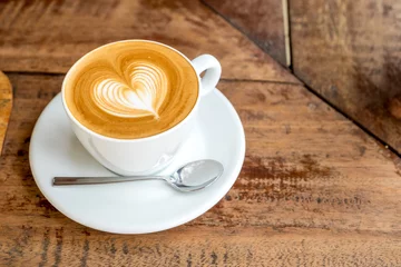 Tuinposter Close-up van witte koffiekopje met hartvorm latte art op houten tabblad © weedezign