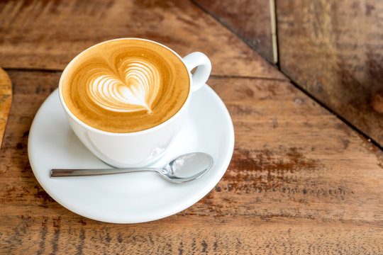 Fototapeta Zamknij się biały kubek kawy z latte art kształcie serca na karcie drewna