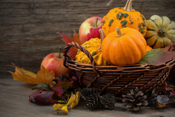 seasonal pumpkins and apples in the basket on wooden table